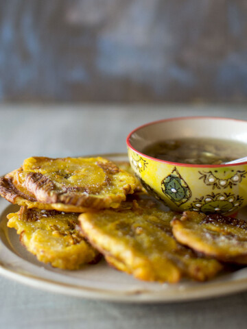 Plate with fried plantains and a bowl with garlic sauce.