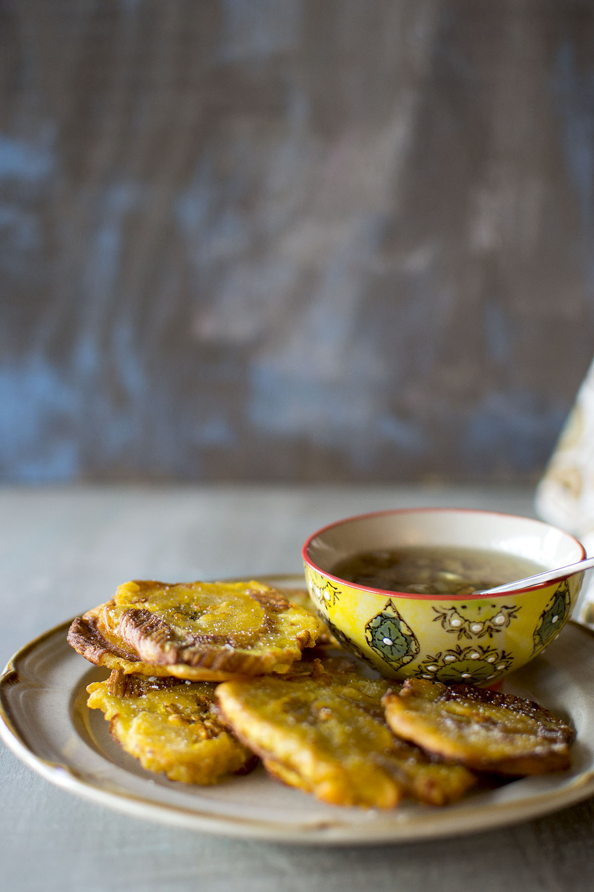 Plate with fried plantains and a bowl with garlic sauce.