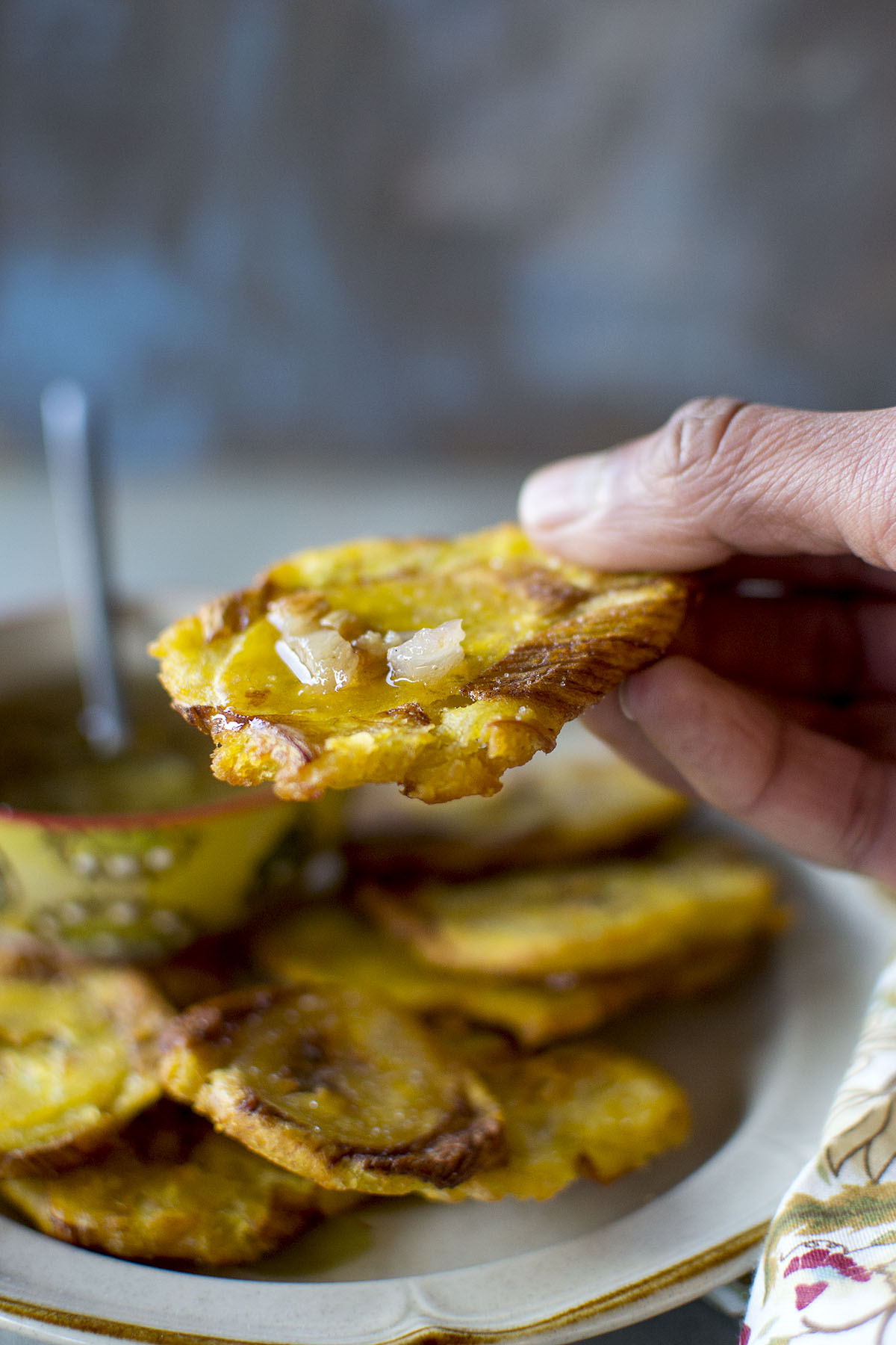 Hand holding a Cuban tostone with mojo sauce.