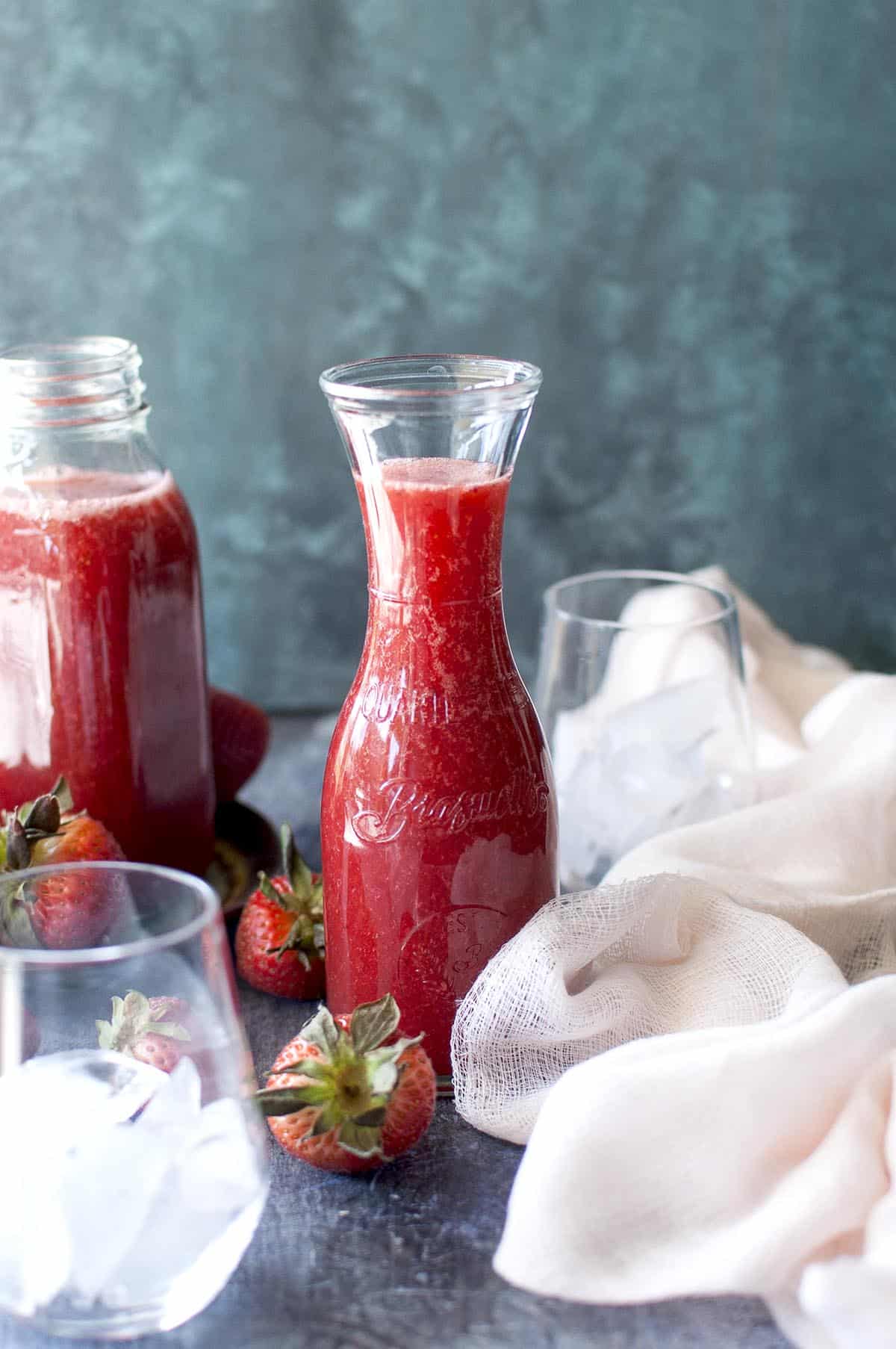 2 glass jars with strawberry crush with fresh berries on the board