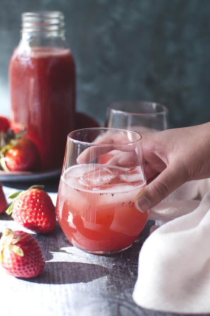 hand holding a glass of juice with ice cubes