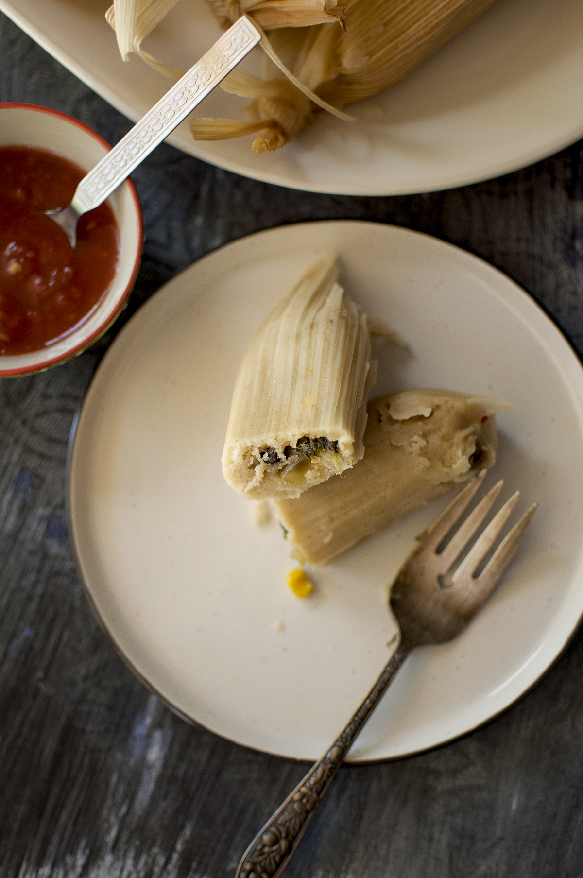 White plate with halved cooked and stuffed masa dough