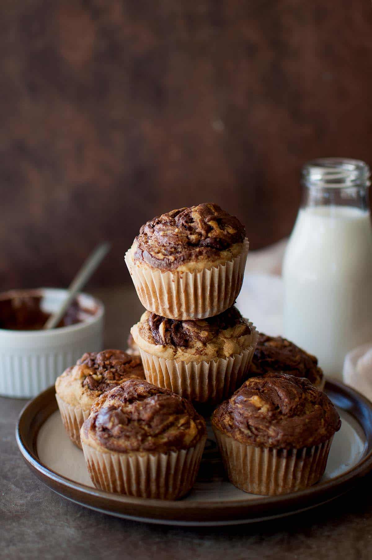 White plate with a stack of Banana Nutella swirl muffins.