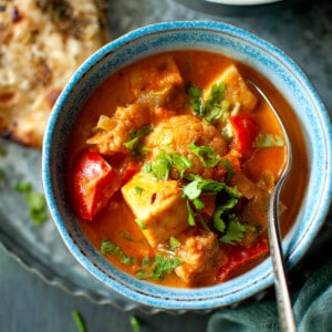 Blue bowl with shahi paneer korma and a spoon.