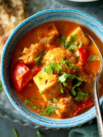 Blue bowl with shahi paneer korma and a spoon.