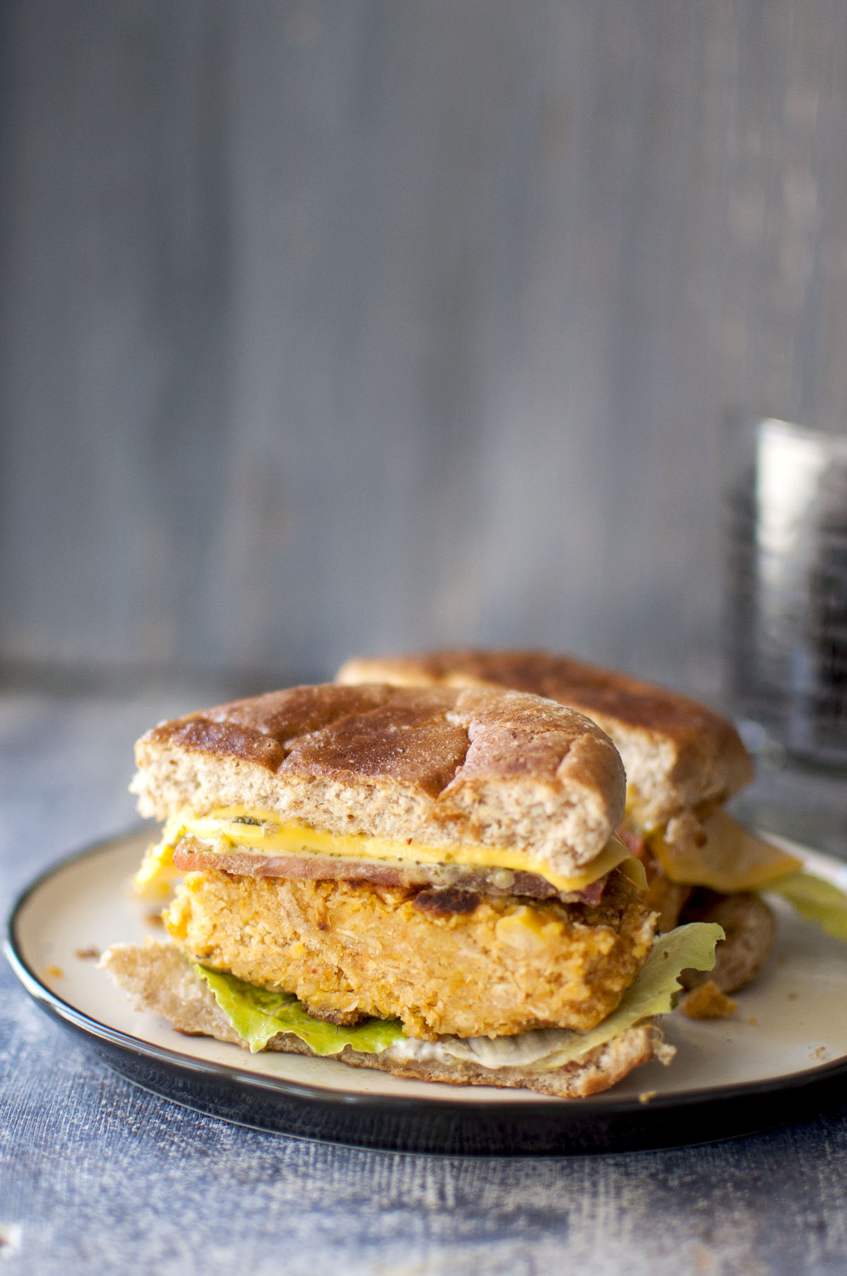 White plate with halved sweet potato chickpea burger sandwich