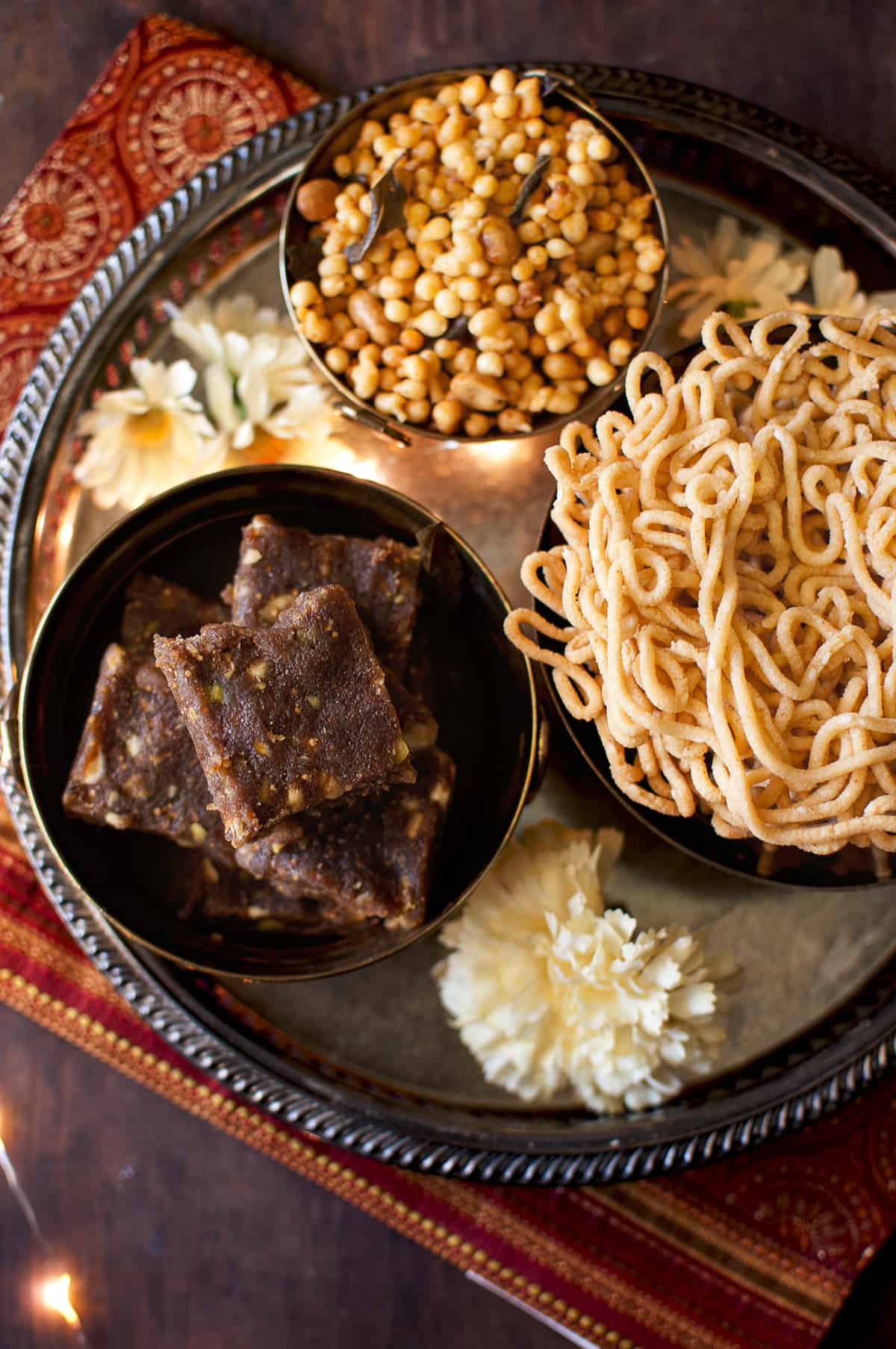 Silver plate with bowls of date nut burfi, murukku and boondi mixture