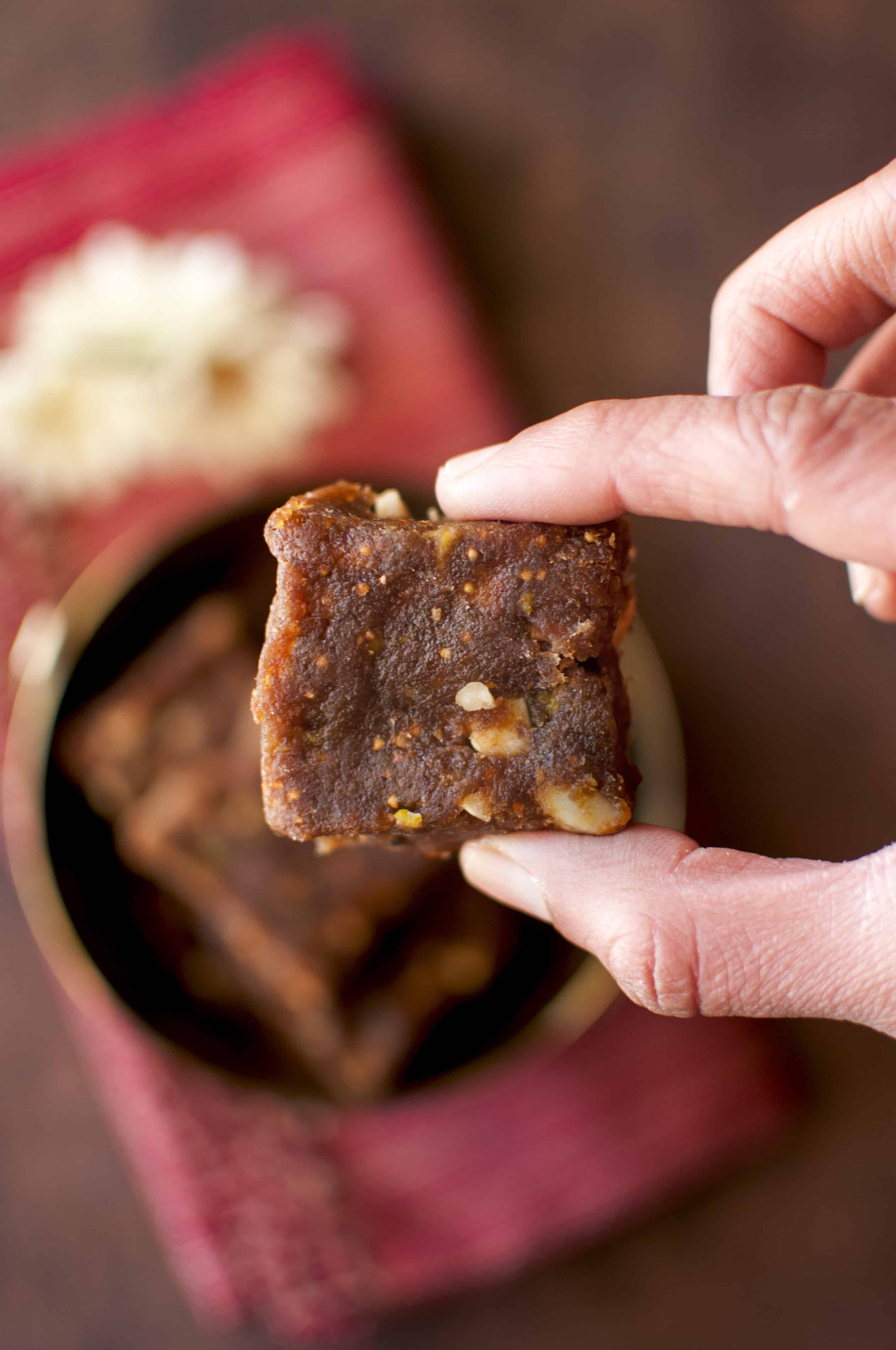 Hand holding a square of date and nut burfi