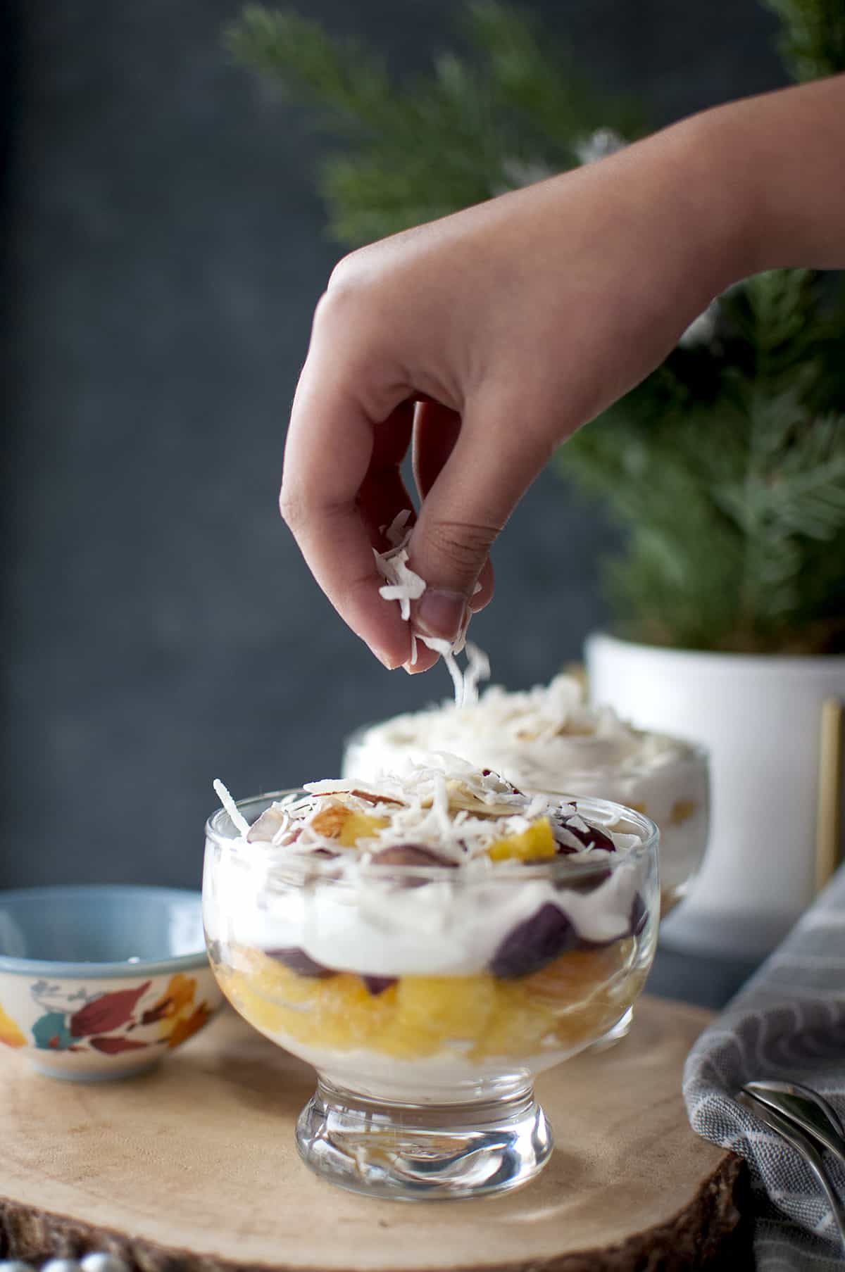 Hand sprinkling grated coconut on fruit salad