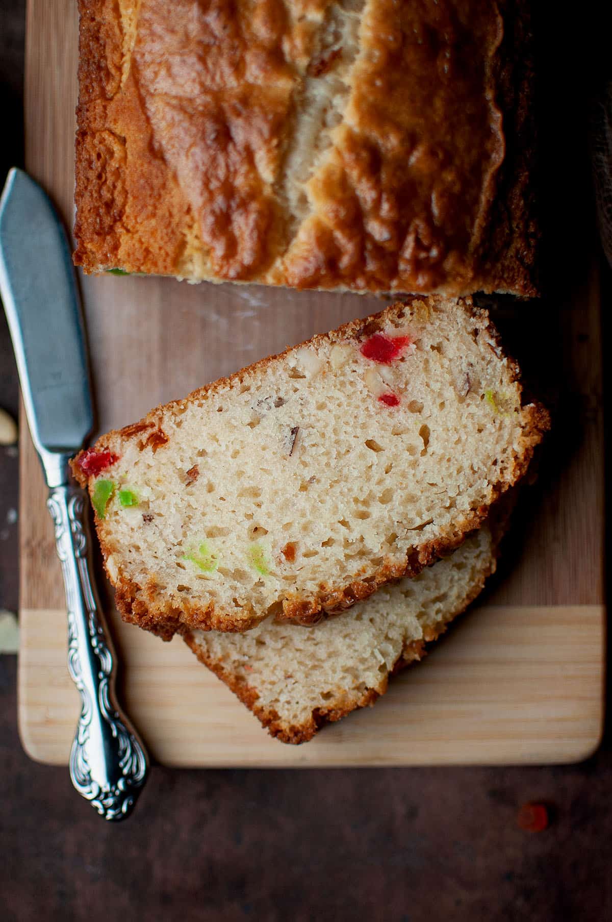 2 slices of eggless fruit nut cake on a wooden board.