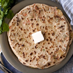 Grey plate with Navratan Paratha topped with a dab of butter