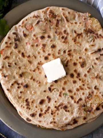 Grey plate with Navratan Paratha topped with a dab of butter