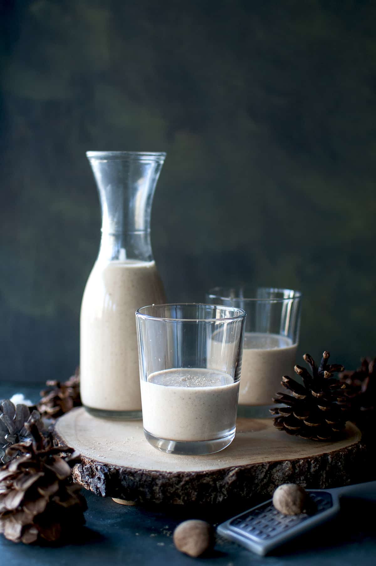 wooden board with 2 glasses and a carafe with vegan eggnog