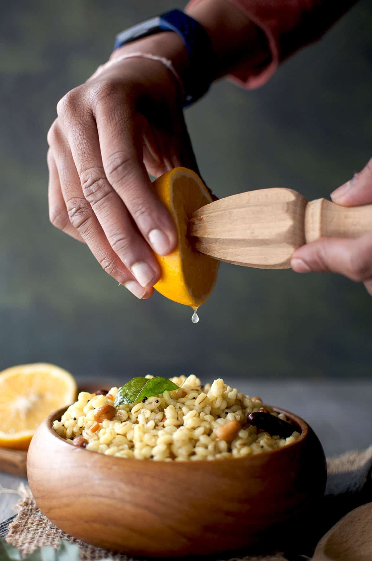 Hand squeezing lemon juice into a wooden bowl