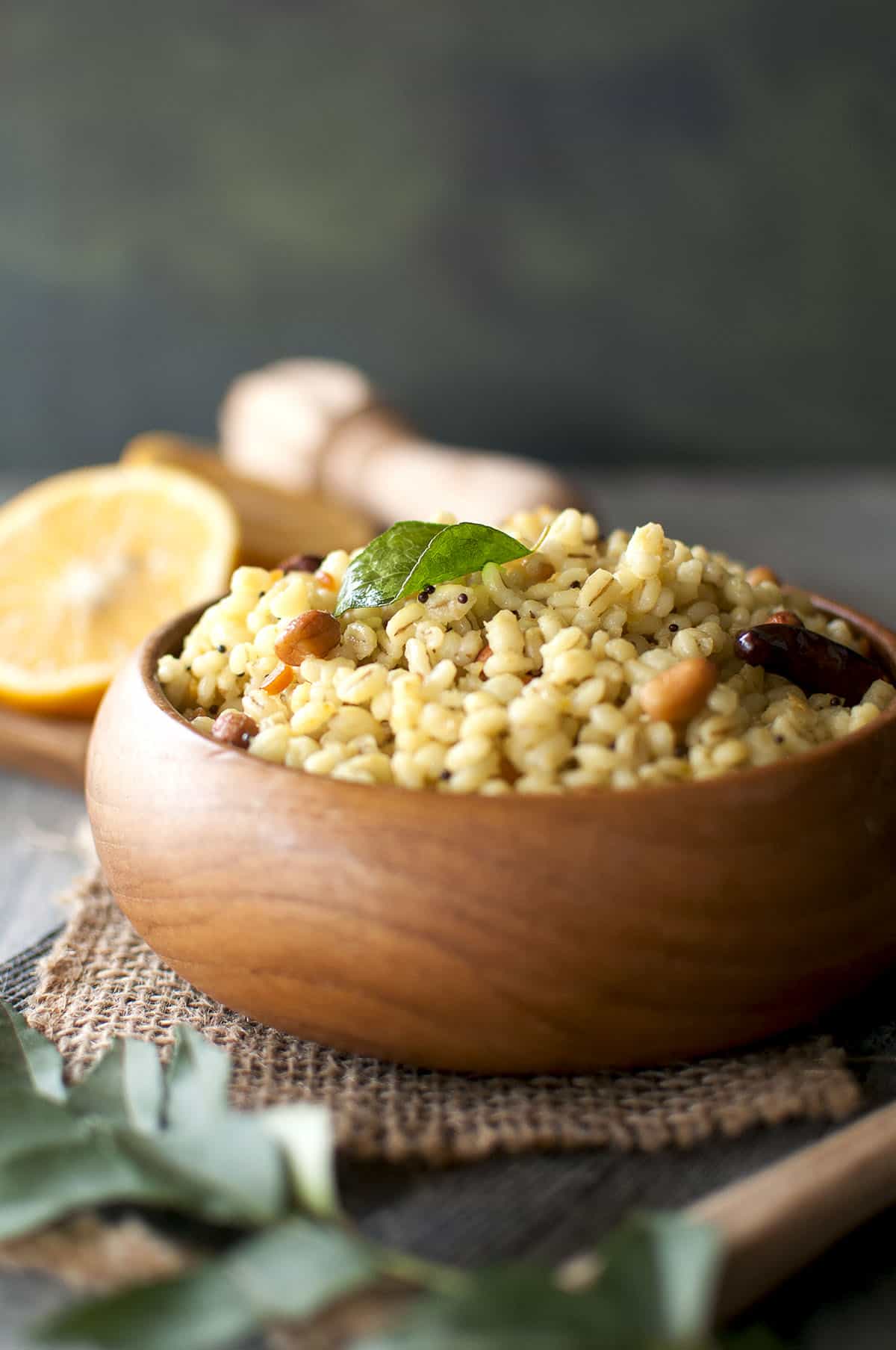 Wooden bowl filled with lemon flavored whole grains topped with curry leaf