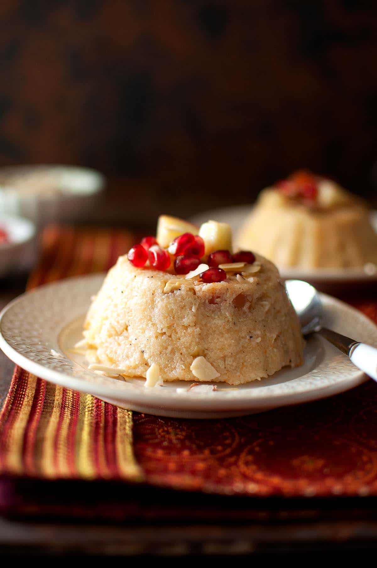 White plate with fruit kesari topped with pomegranate arils