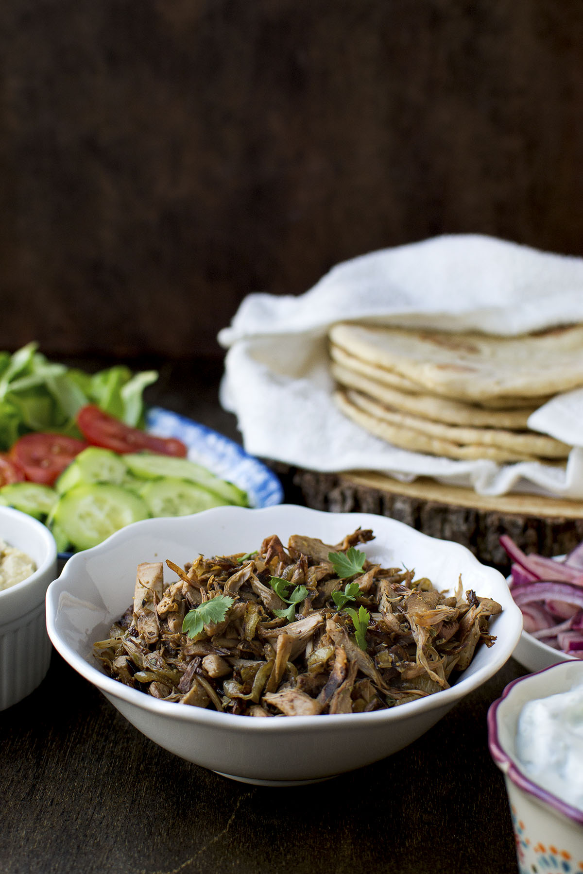 White bowl with jackfruit and flatbreads in the background