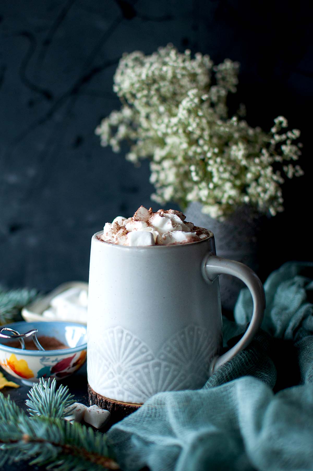 Grey mug with hot chocolate topped with whipped cream and marshmallows