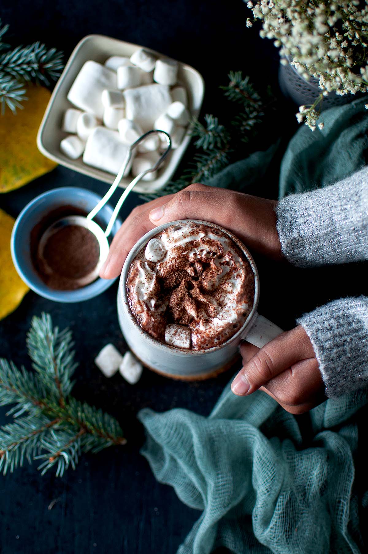 Hand holding a grey mug with hot cocoa with cacao powder