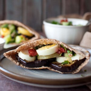 Brown plate with half eggplant pita sandwich.