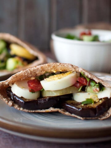 Brown plate with half eggplant pita sandwich.