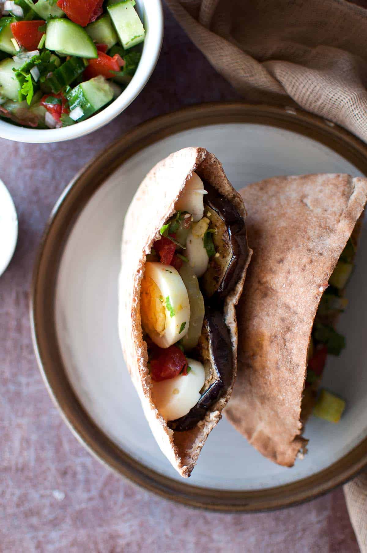 Brown plate with half stuffed pita pocket.