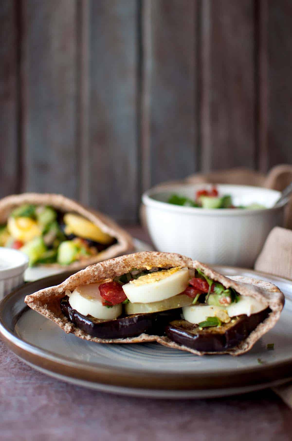 Brown plate with half of a Sabich sandwich.