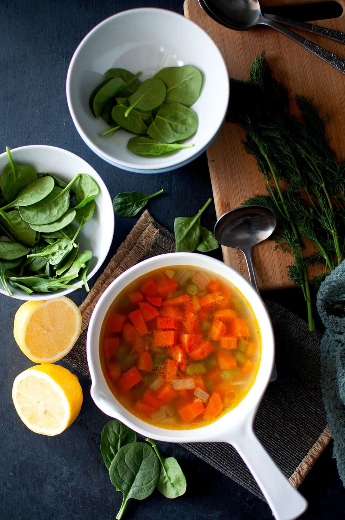 White bowl with carrot green bean soup and bowls with spinach.