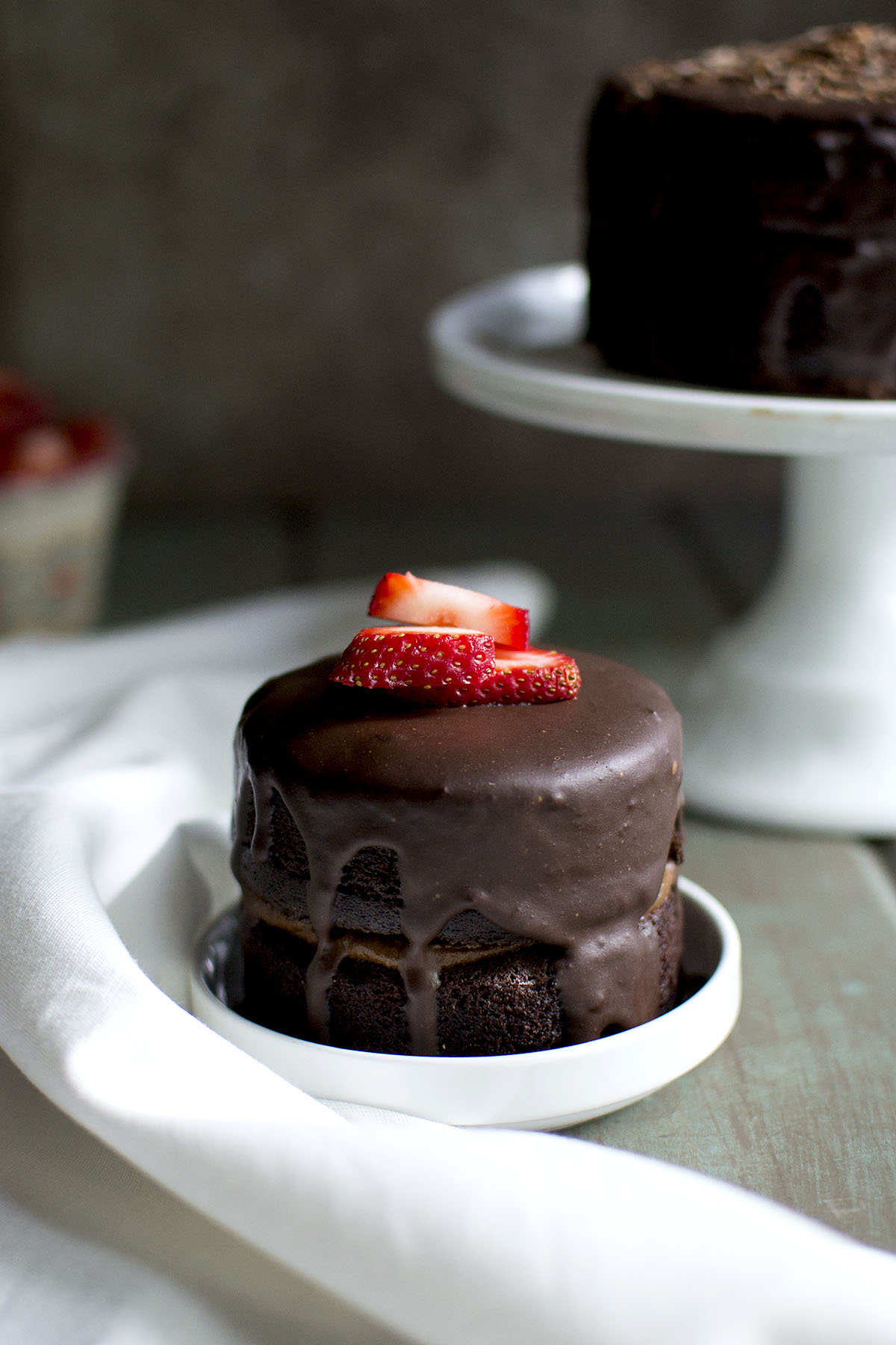 White bowl with small cake topped with strawberries