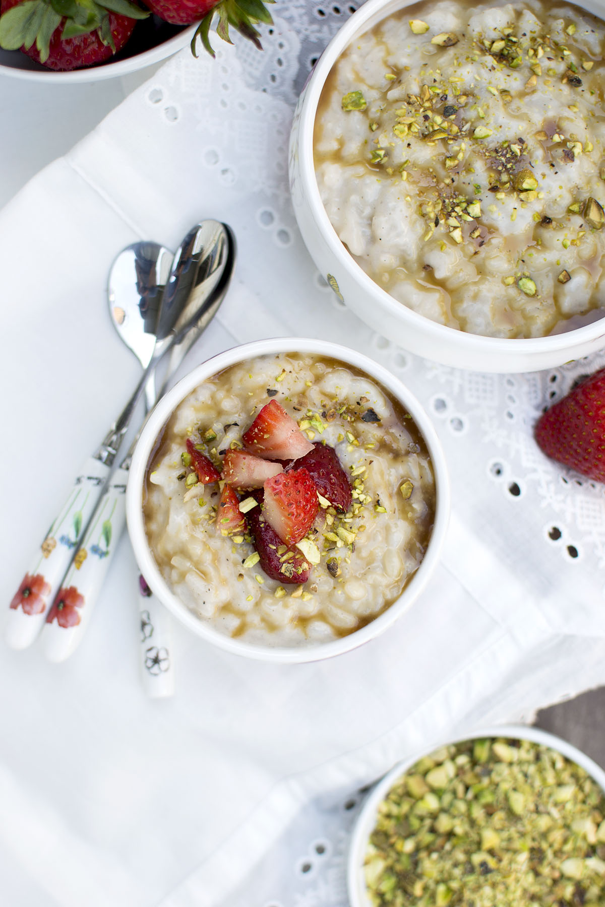 White bowl with rice pudding topped with caramel sauce, chopped berries and nuts