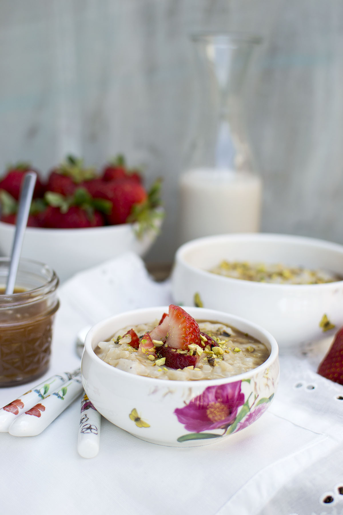 White bowl with rice pudding topped with chopped berries and nuts