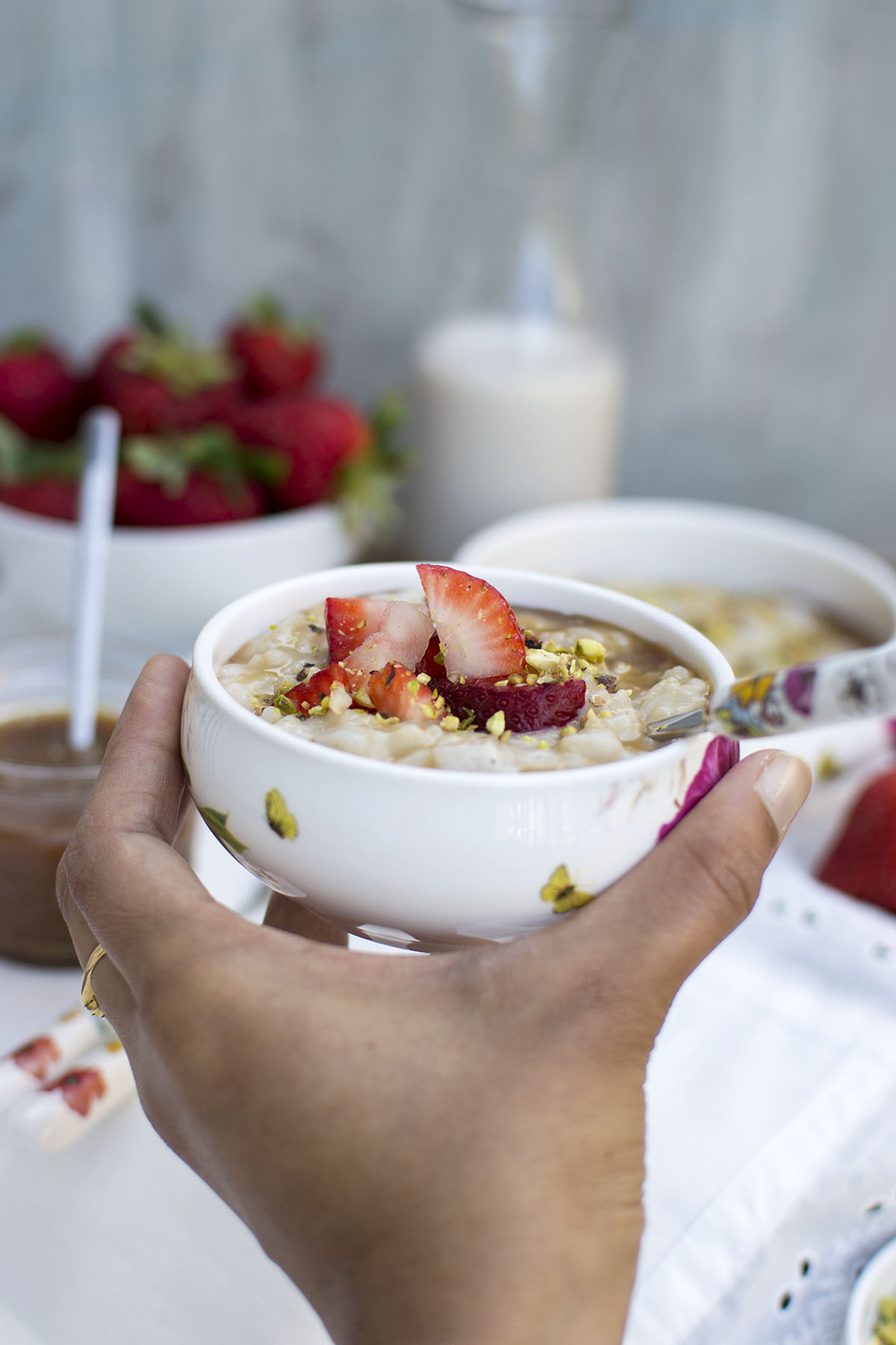 Hand holding a bowl with dessert topped with berries and nuts