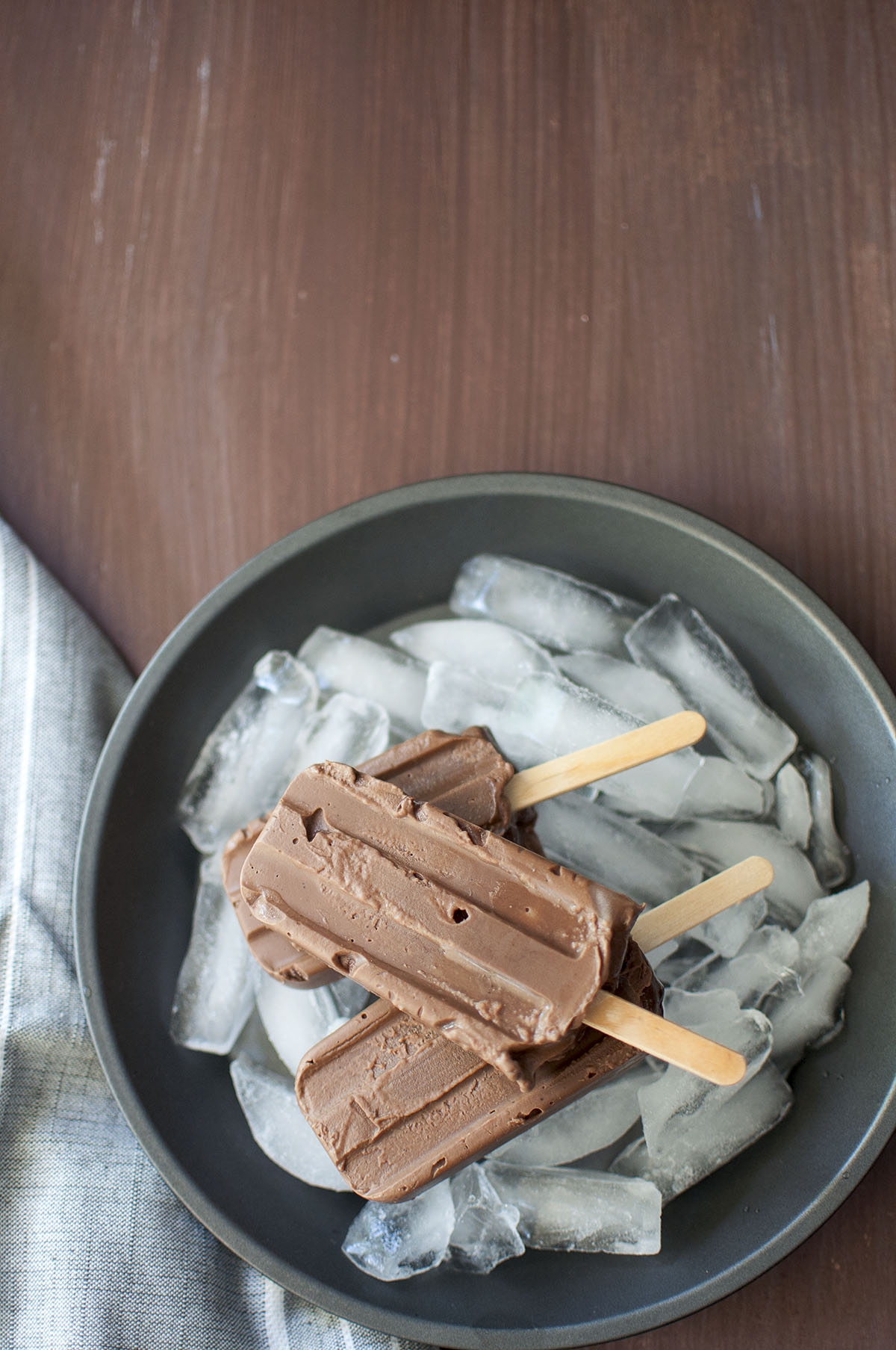 Grey pan with 3 chocolate pudding pops over ice cubes