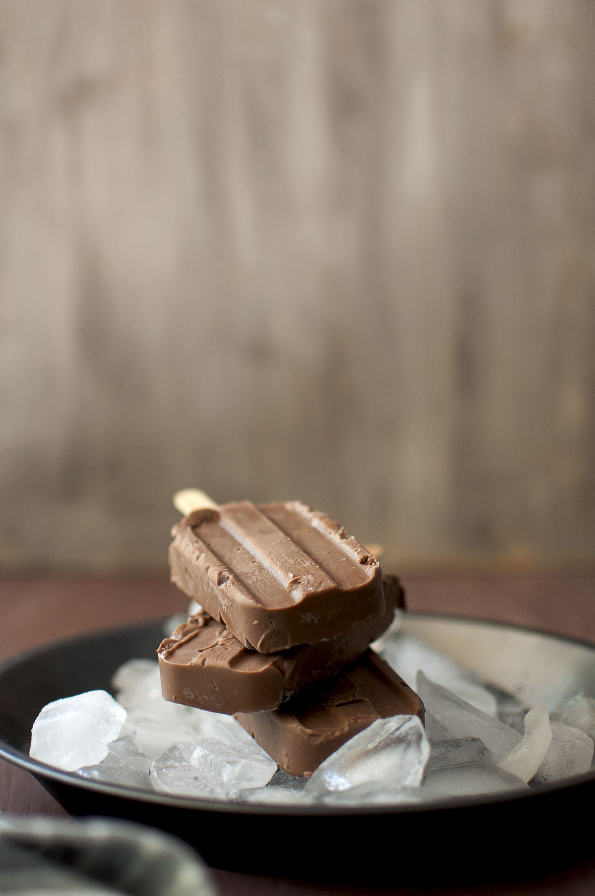 Grey pan with ice cubes and a stack of 3 chocolate popsicles