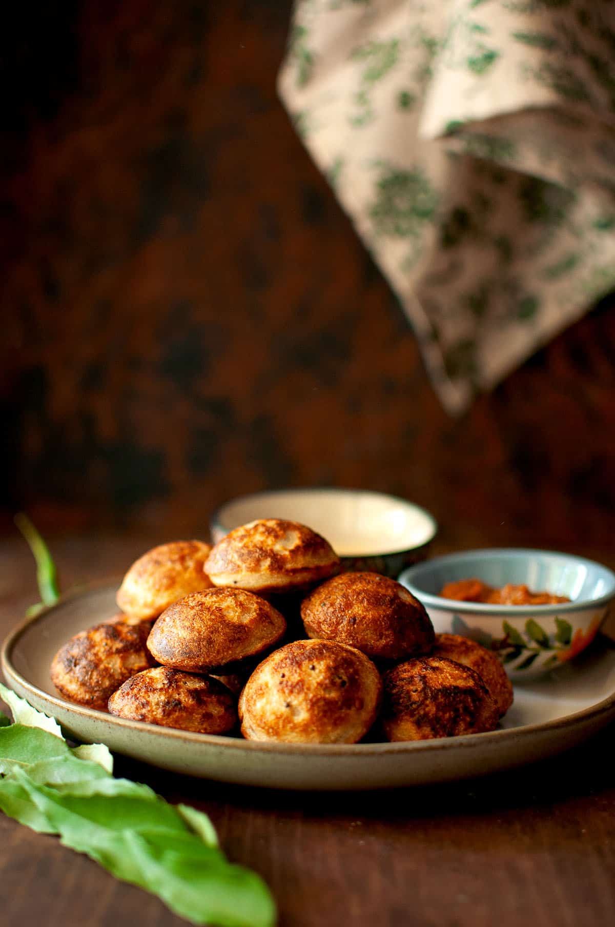 Grey plate with a stack of wheat paniyaram.