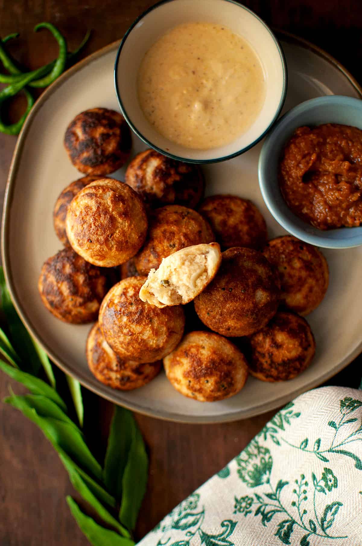 Grey plate with instant ponganalu and bowls of chutneys.