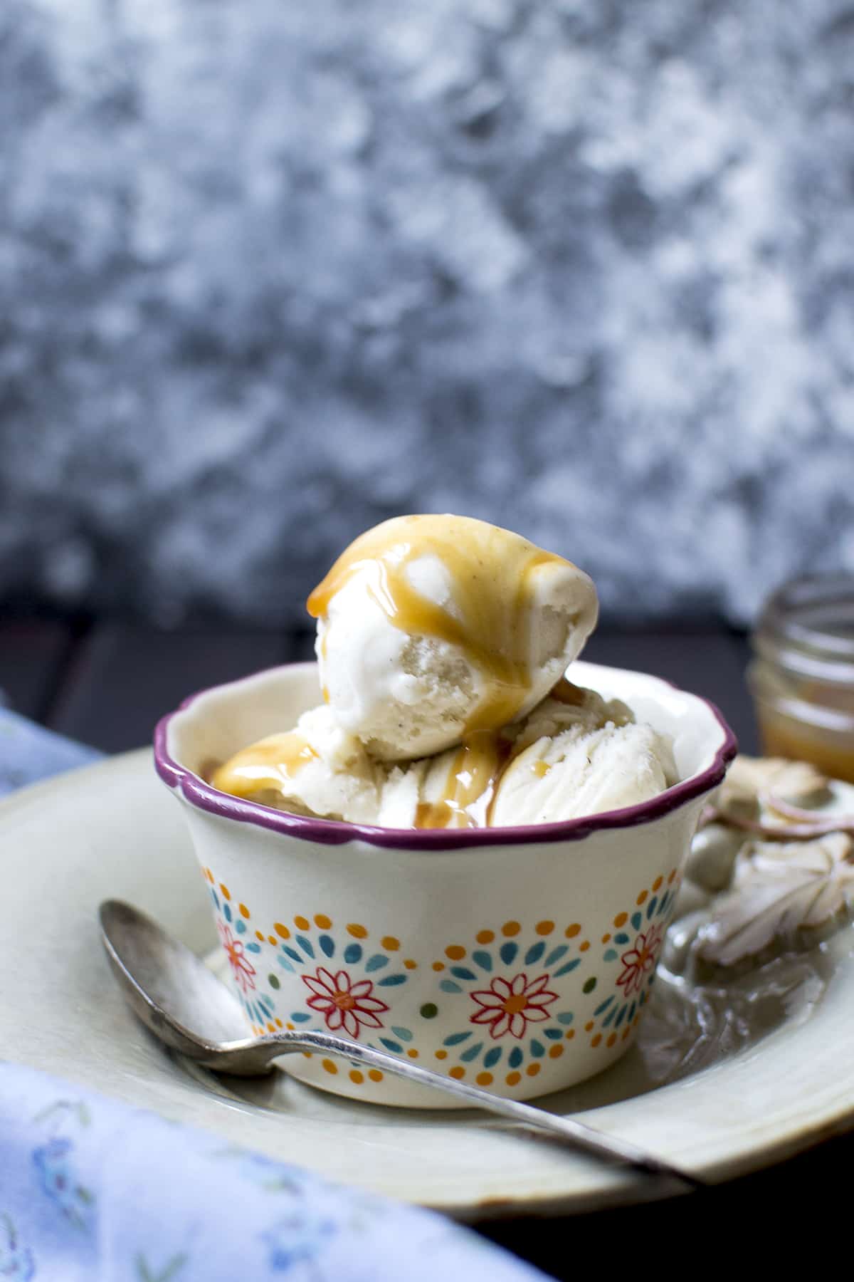 White bowl with scoops of ice cream and a drizzle of caramel sauce