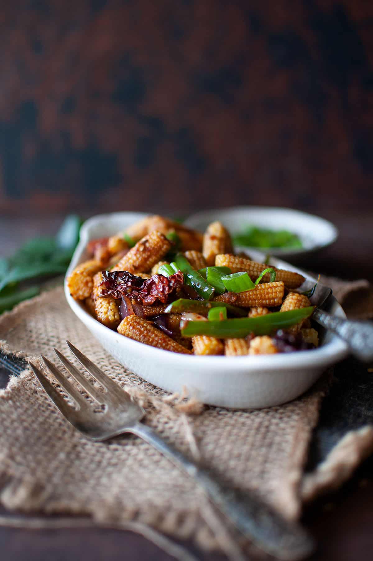 White bowl with roast baby corn.