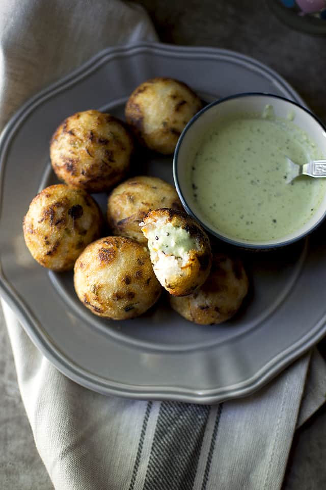 Grey plate with south indian savory aebleskivers with a small bowl of chutney