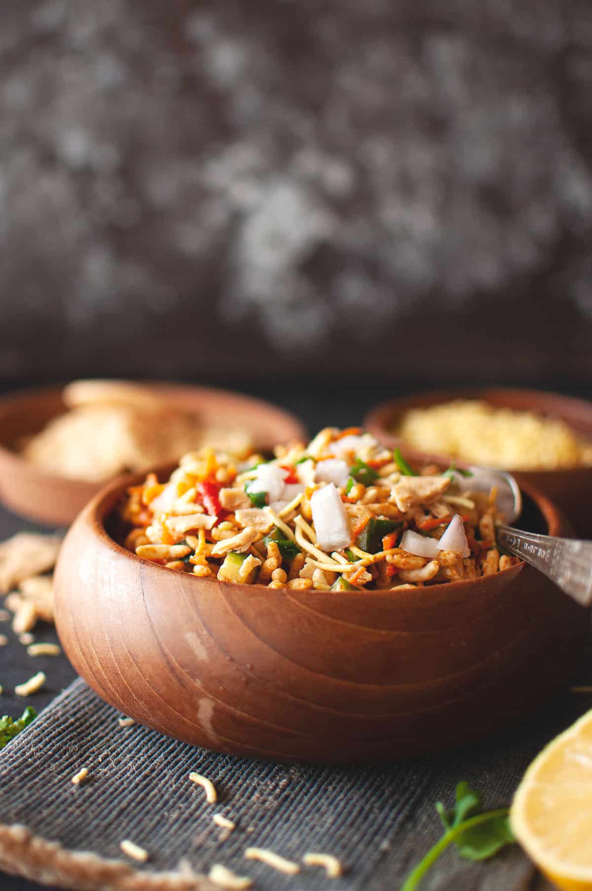Wooden bowl of murmure chaat with vegetables.