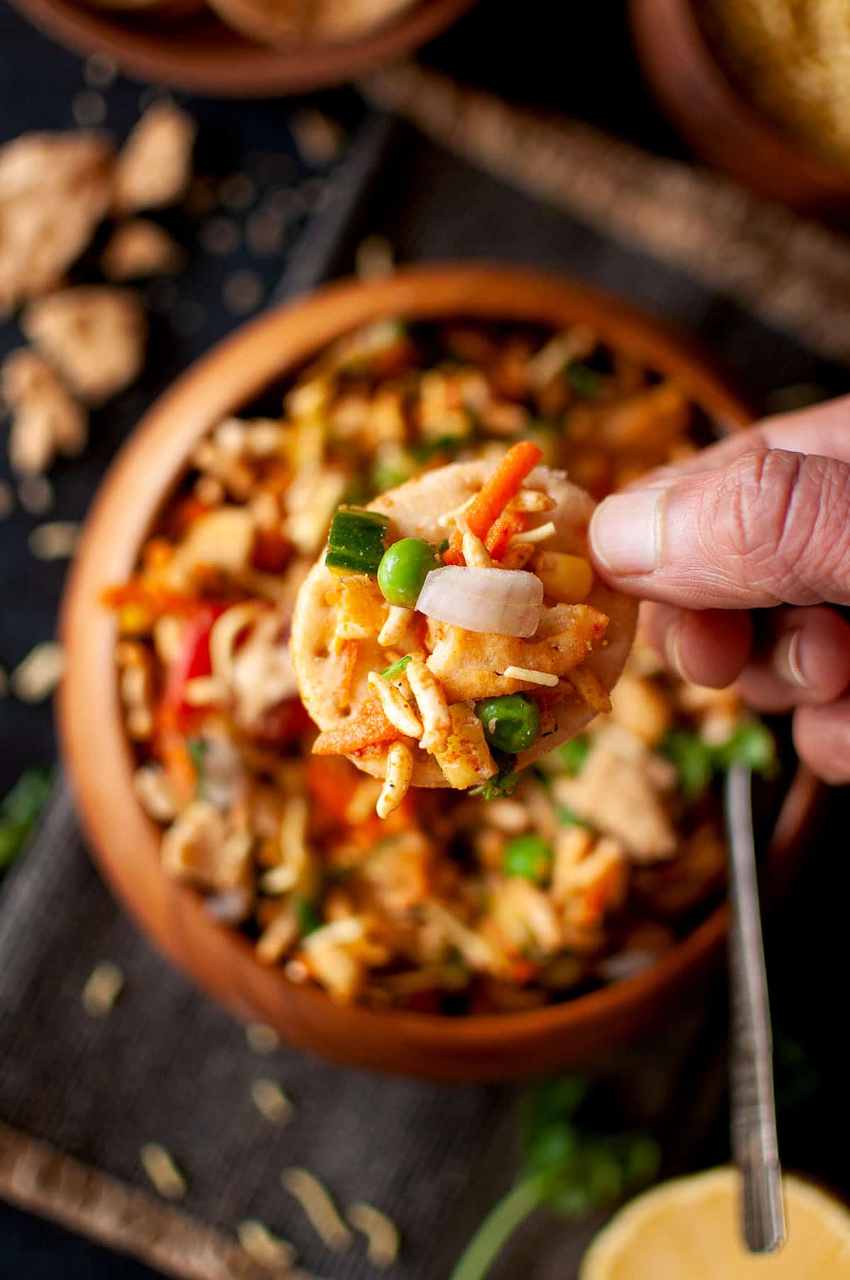 Hand holding a papdi topped chaat.