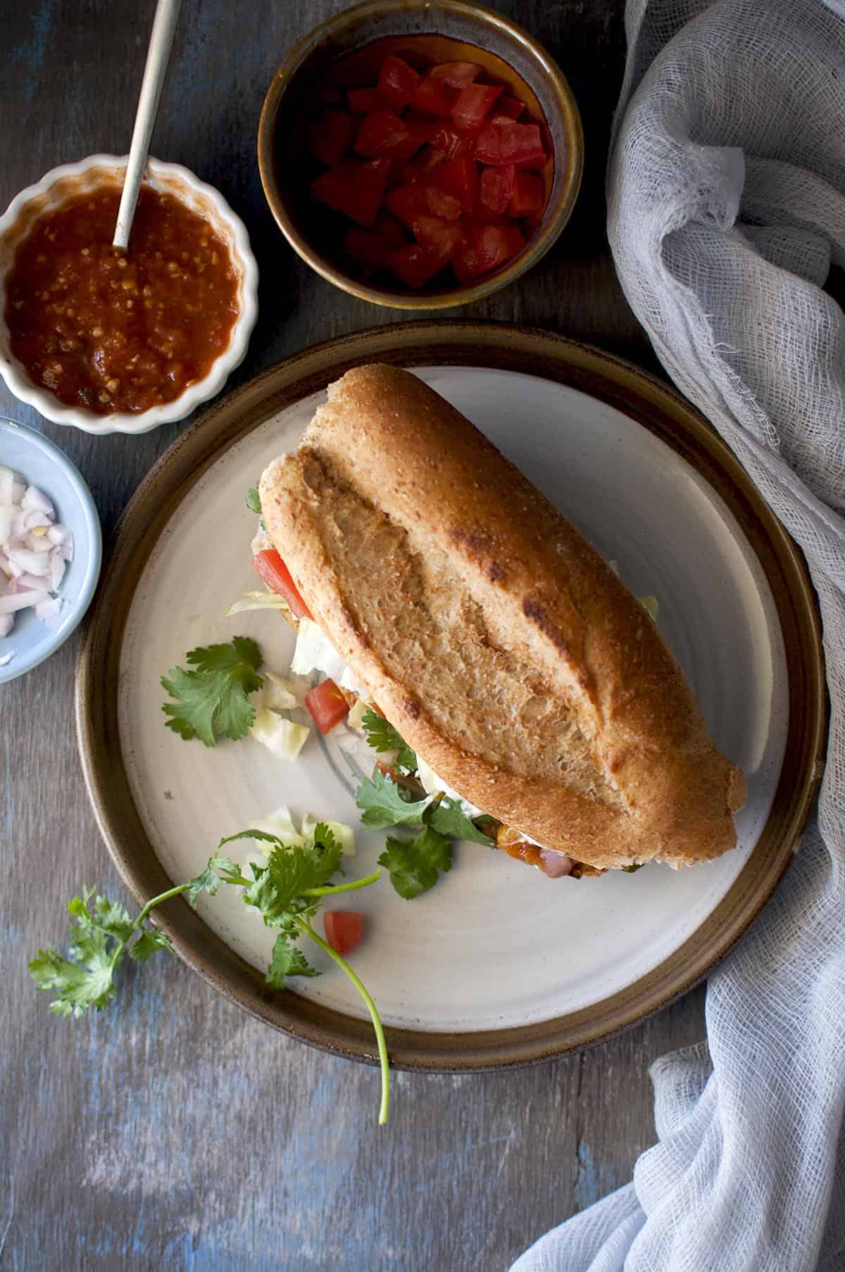 Top of a Grey plate with sandwich and a cilantro sprig on the side