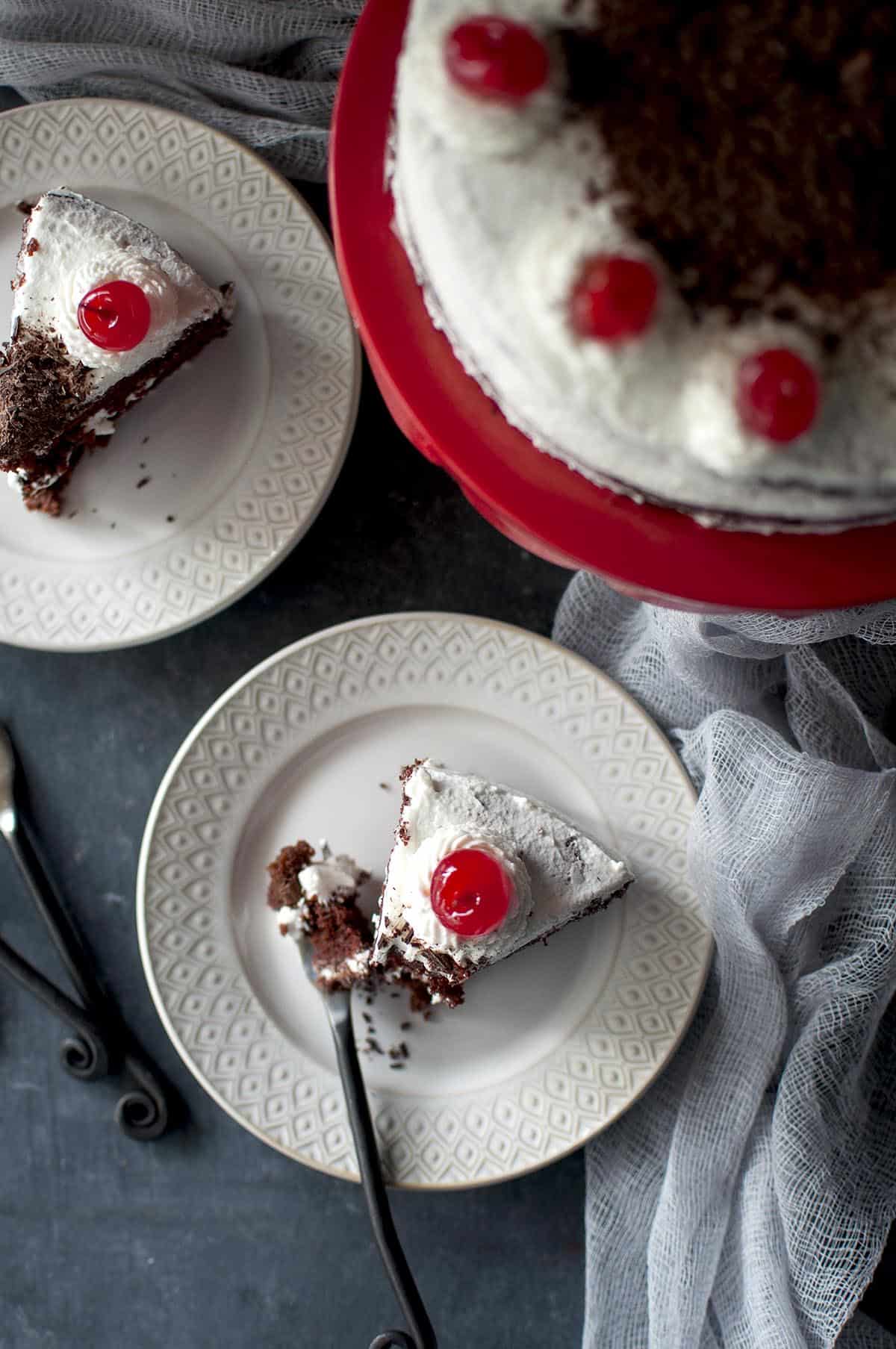 Top view of a slice of black forest cake topped with cherry on a white plate