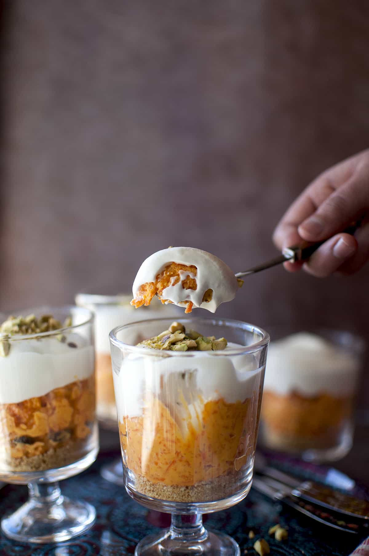 Hand holding a spoon with creamy halwa.