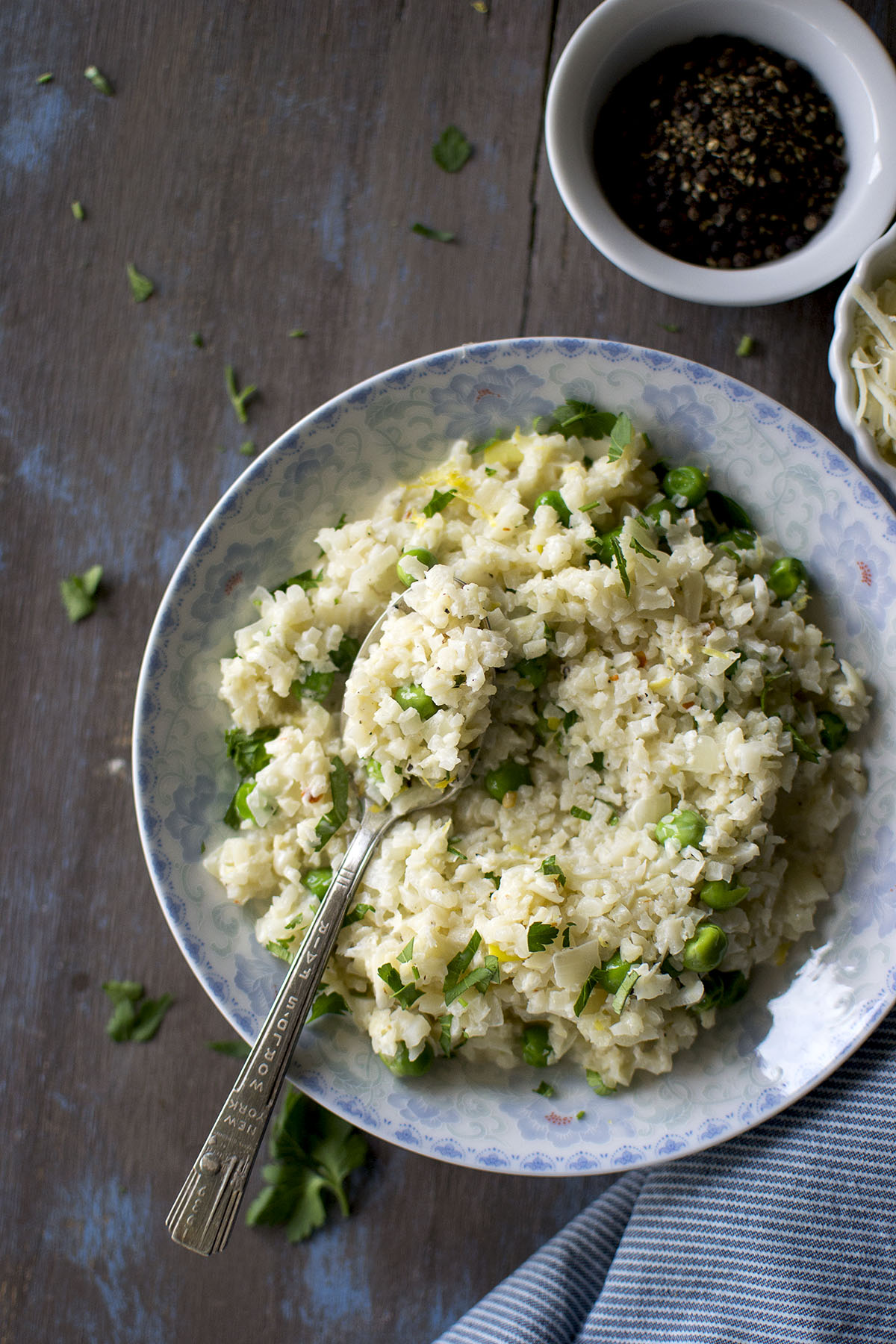 White bowl with cauliflower rice, green peas and a spoon