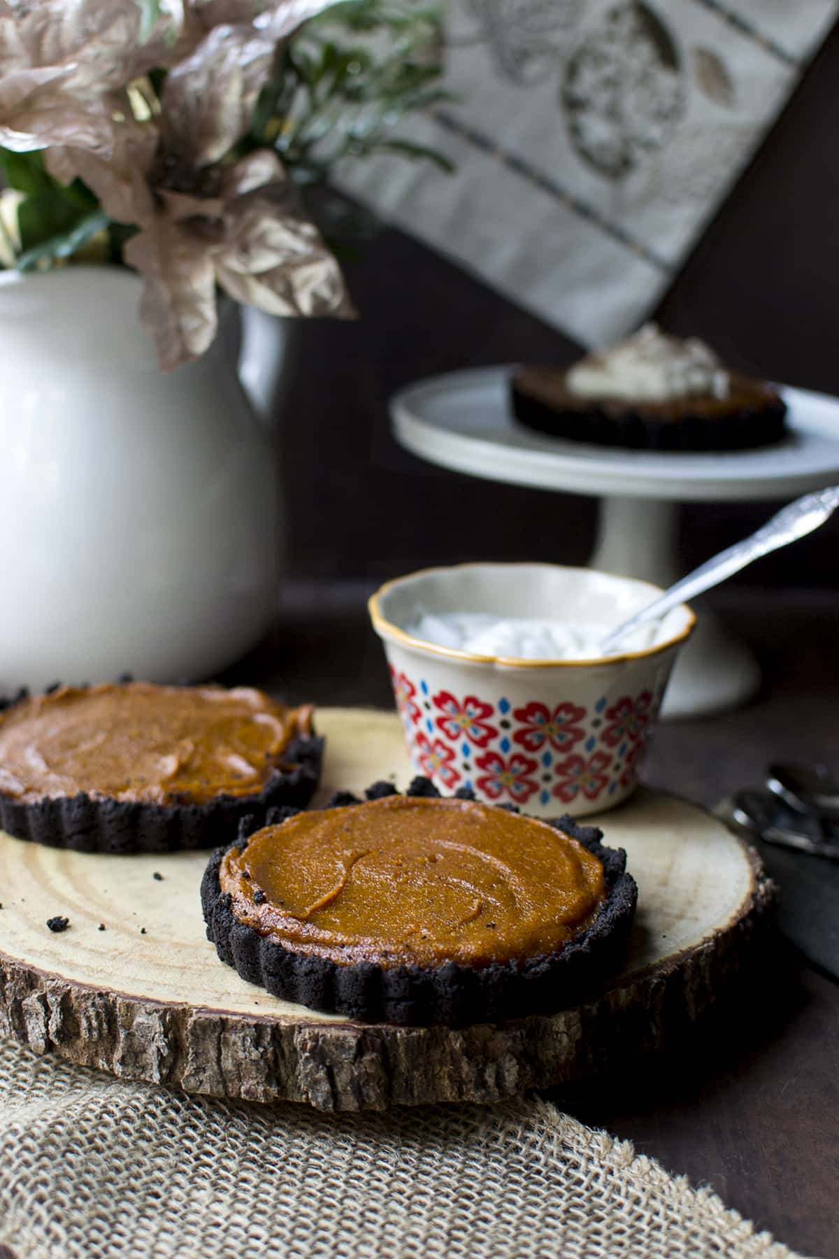 Wooden board with 2 mini tarts and coconut whipped cream in the background