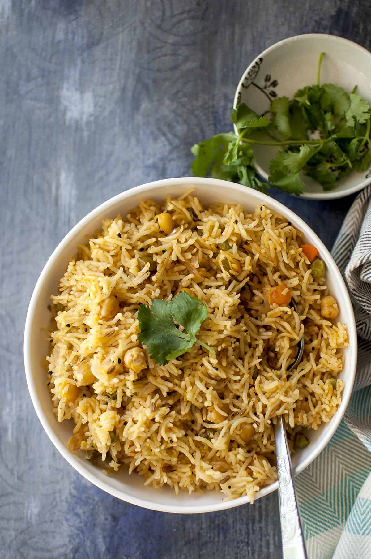 White bowl with Achari vegetable Pulao with a cilantro sprig on top