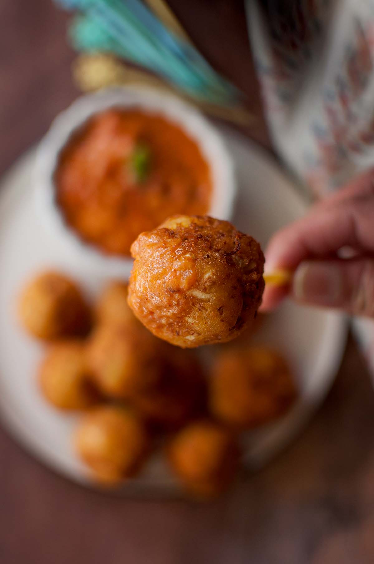 Hand holding a gobi kofta on a pick