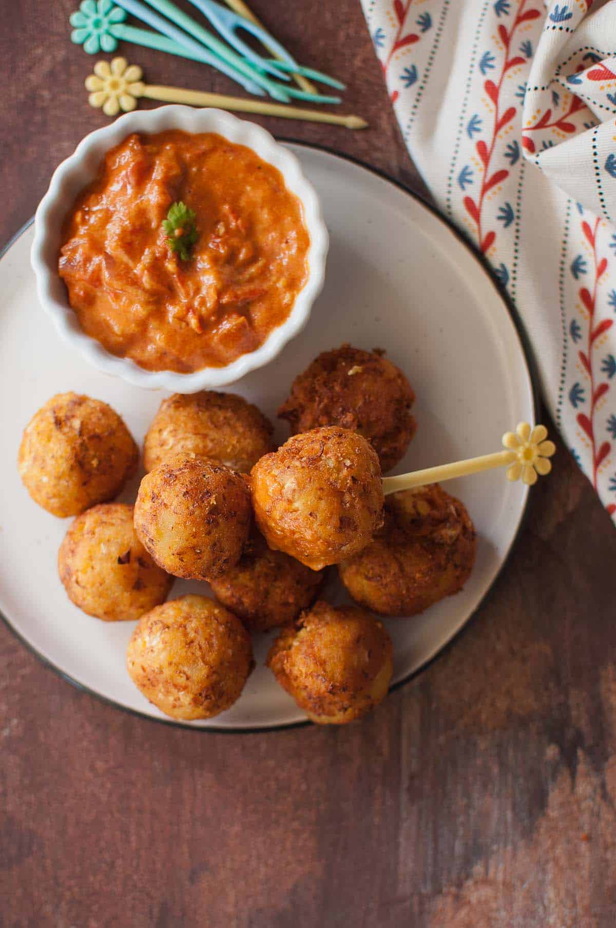 White plate with veggie balls and tomato sauce in a bowl