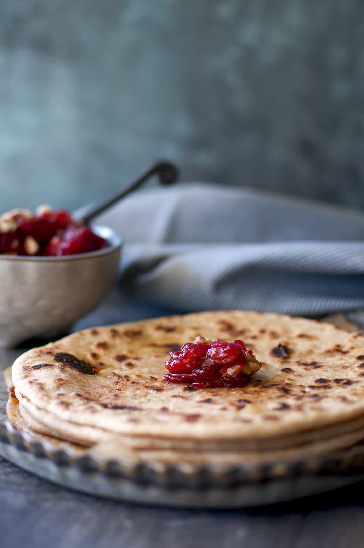 Stack of paratha topped with a dollop of cranberries chutney